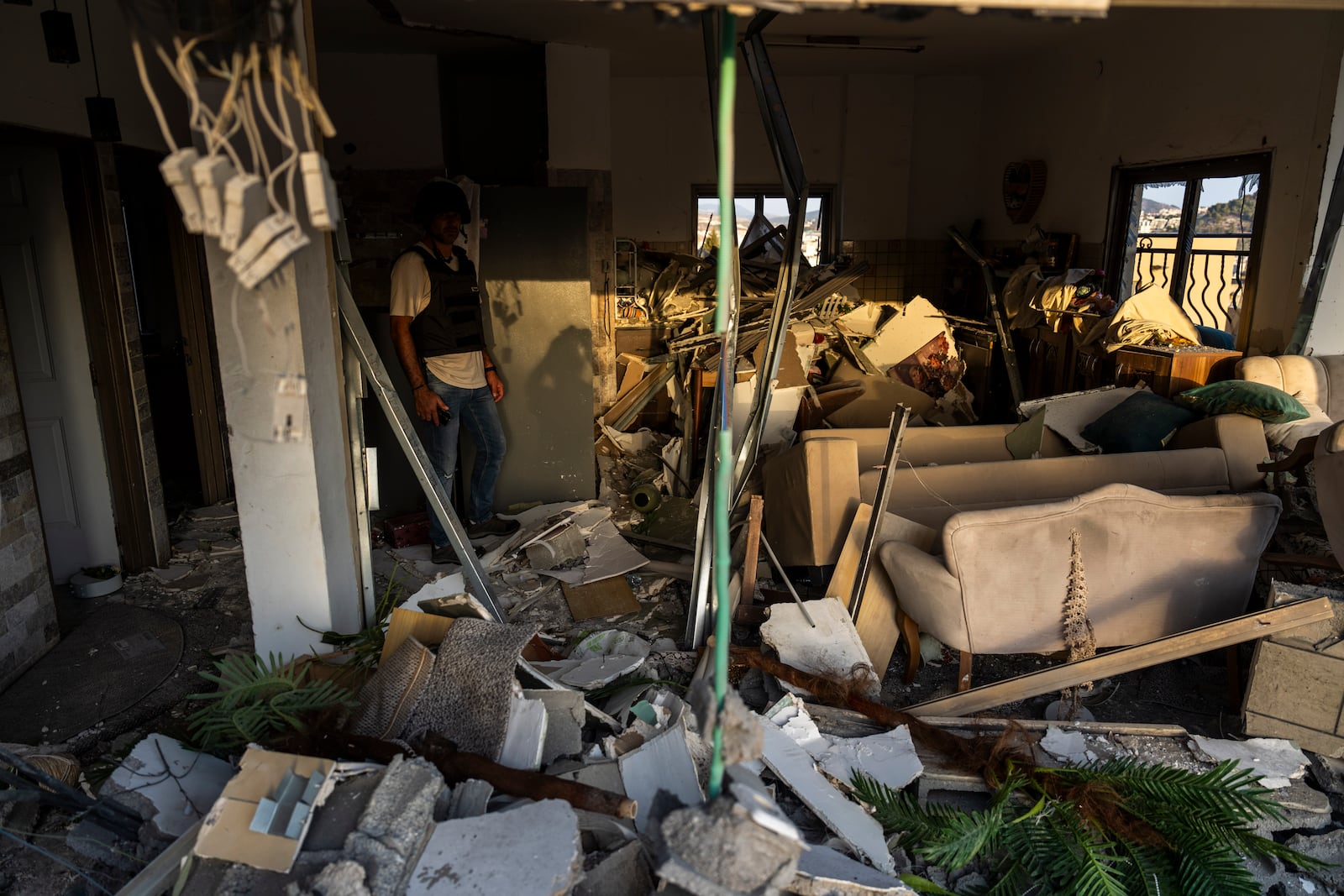 An Israeli security forces officer examines the damage to a home struck by a rocket fired from Lebanon in the town of Majd al-Krum, northern Israel, Wednesday, Oct. 16, 2024. (AP Photo/Ariel Schalit)