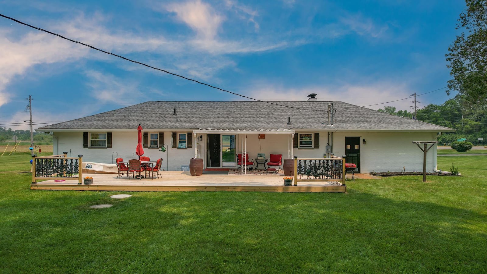 The rear of the home has a covered patio and a new attached deck with partial railings. Exterior doors include a sliding glass door off the dining room and another door off the garage.