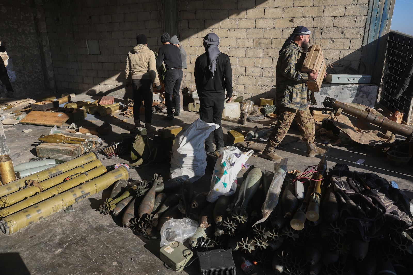 Syrian opposition fighters seize abandoned Syrian army ammunition in in the town of Khan Assubul, Syria, southwest of Aleppo, Sunday, Dec. 1, 2024. Syrian opposition insurgency launched a campaign on Wednesday with a two-pronged attack on Aleppo and the countryside around Idlib.(AP Photo/Ghaith Alsayed)