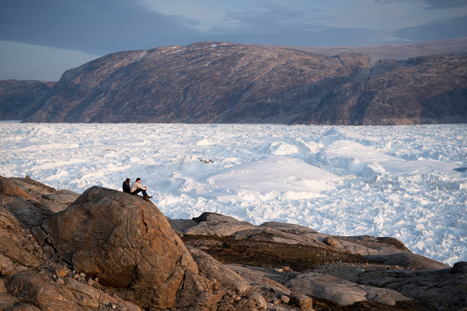 FILE - New York University student researchers sit on a rock overlooking the Helheim glacier in Greenland, Aug. 16, 2019. (AP Photo/Felipe Dana, File)