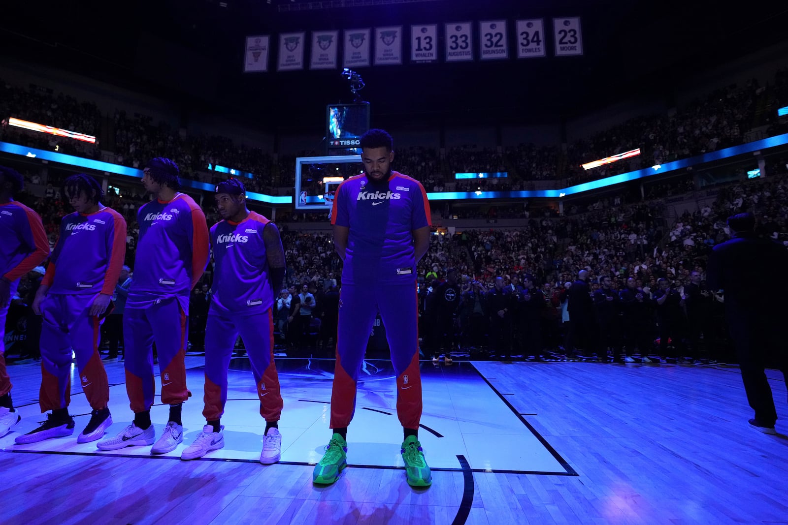 New York Knicks center Karl-Anthony Towns, center, stands on the court as the national anthem is played before an NBA basketball game against the Minnesota Timberwolves, Thursday, Dec. 19, 2024, in Minneapolis. (AP Photo/Abbie Parr)