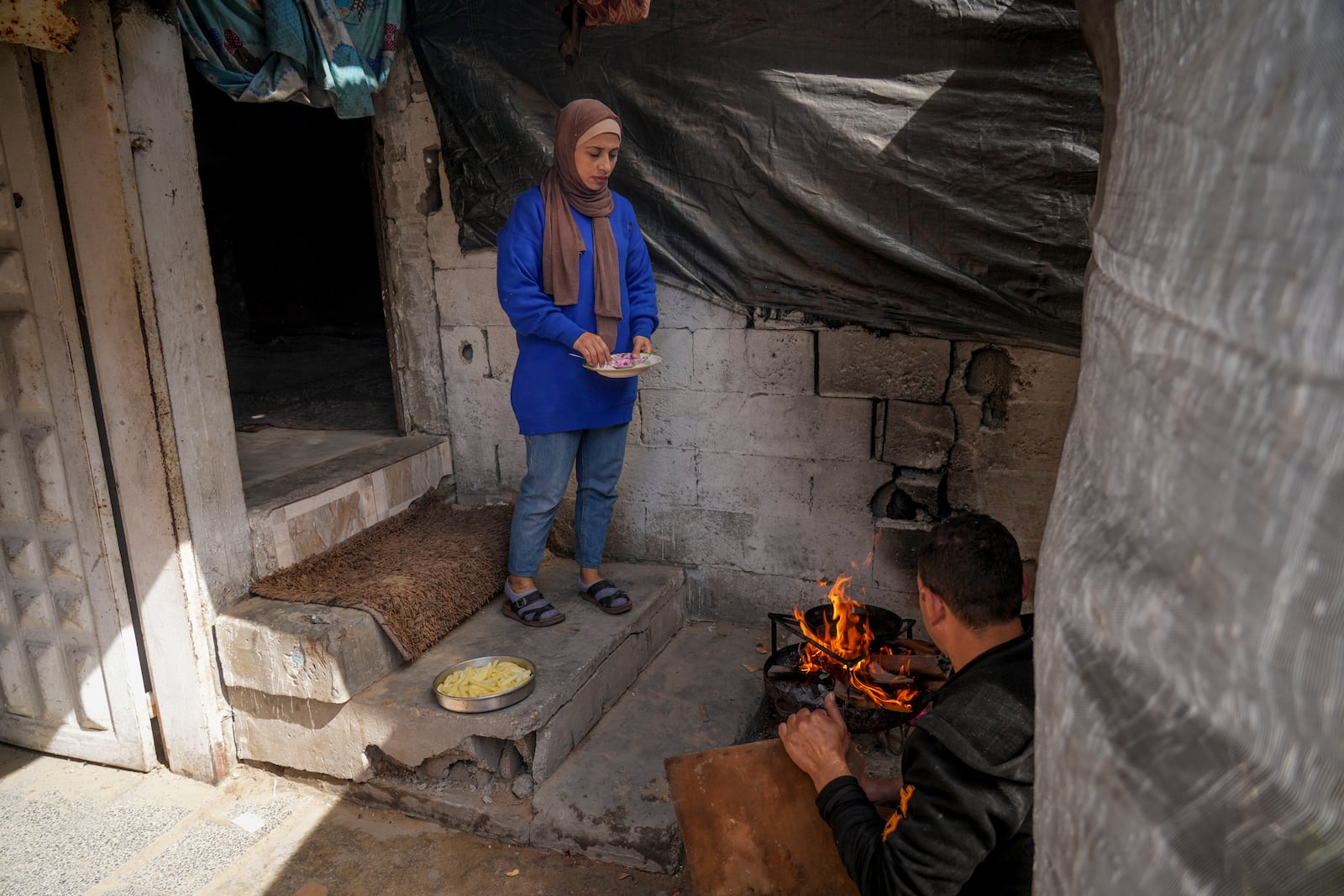 Rawya Tamboura and her husband Ahmed prepare a meal in their home, which was struck by an Israeli airstrike on Oct. 20, 2023, in Beit Lahiya, northern Gaza Strip, Friday, Feb. 21, 2025. (AP Photo/Abdel Kareem Hana)