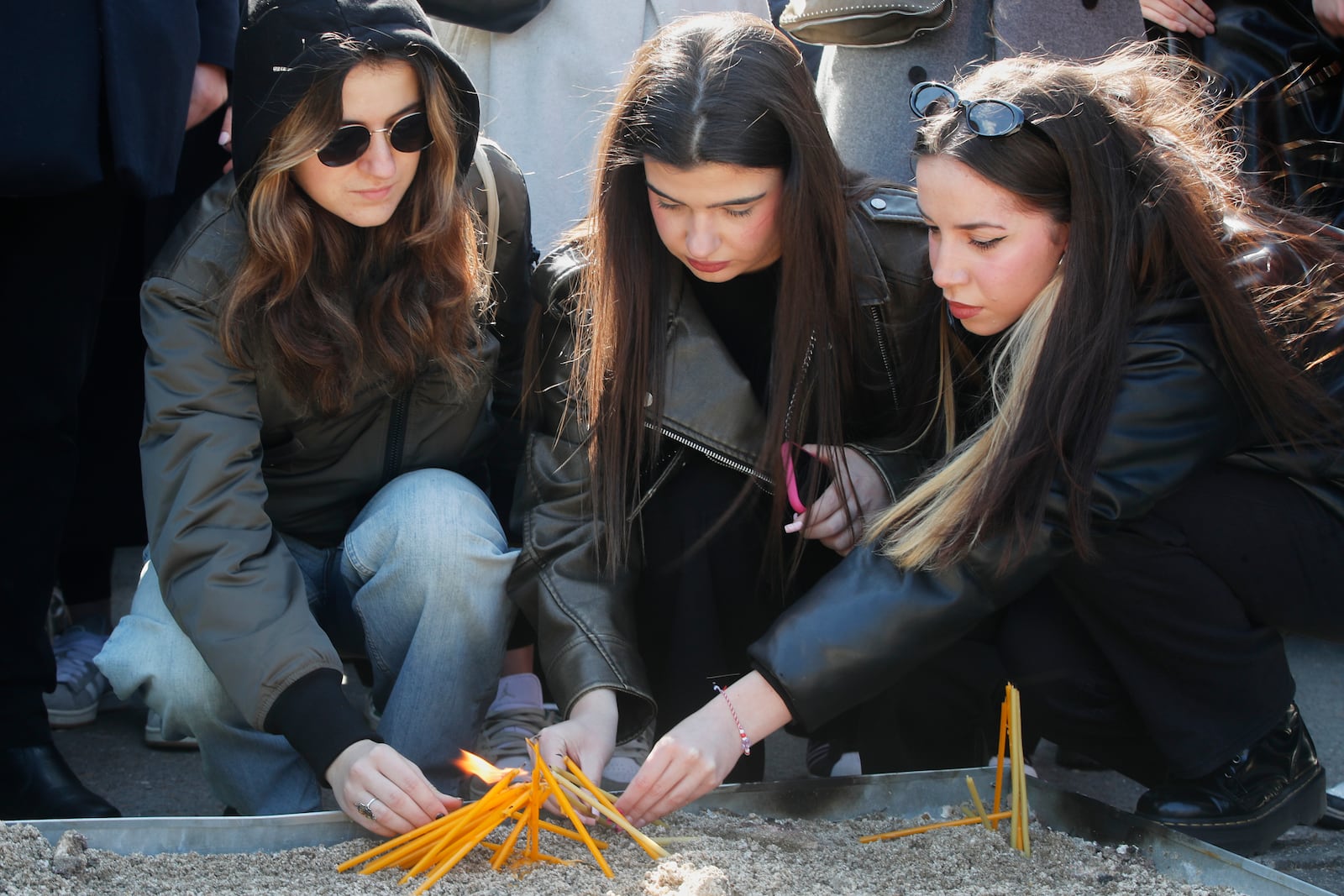 University students light candles for the victims of a massive nightclub fire in the town of Kocani, in Skopje, North Macedonia, Tuesday, March 18, 2025. (AP Photo/Boris Grdanoski)