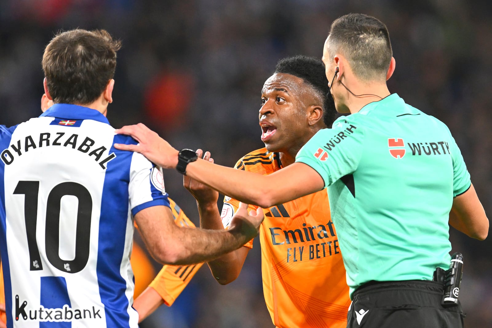 Real Sociedad's Mikel Oyarzabal, left, argues with Real Madrid's Vinicius Junior, centre, during the Spanish Copa del Rey soccer match between Real Sociedad and Real Madrid at the Reale Arena in San Sebastian, Spain, Wednesday, Feb. 26, 2025. (AP Photo/Miguel Oses)