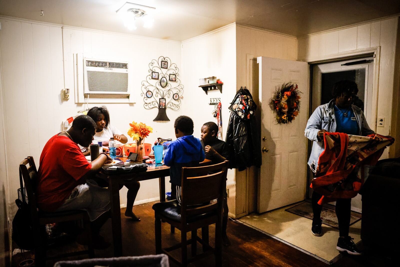 Ira Butler's four children eat dinner in their living room. There are photos of their deceased father all over the walls of their home. JIM NOELKER/STAFF