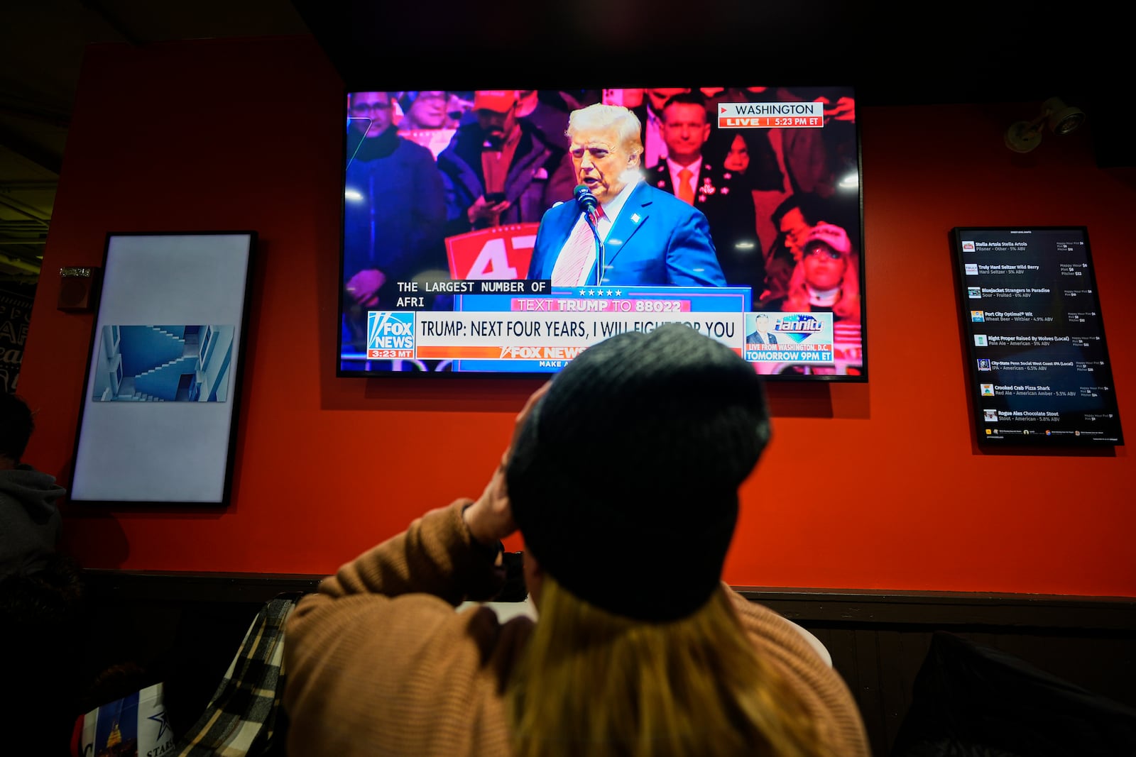 A woman watches President-elect Donald Trump speak at a rally ahead of the 60th Presidential Inauguration, Sunday, Jan. 19, 2025, in Washington. (AP Photo/Mike Stewart)