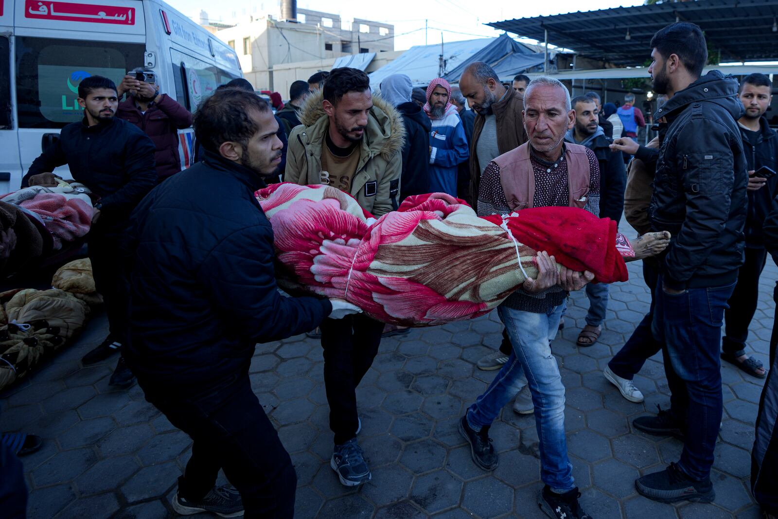 Palestinians carry the body of a relative killed in the Israeli bombardment of the Gaza Strip at a hospital in Deir al-Balah, Sunday, Dec. 15, 2024. (AP Photo/Abdel Kareem Hana)