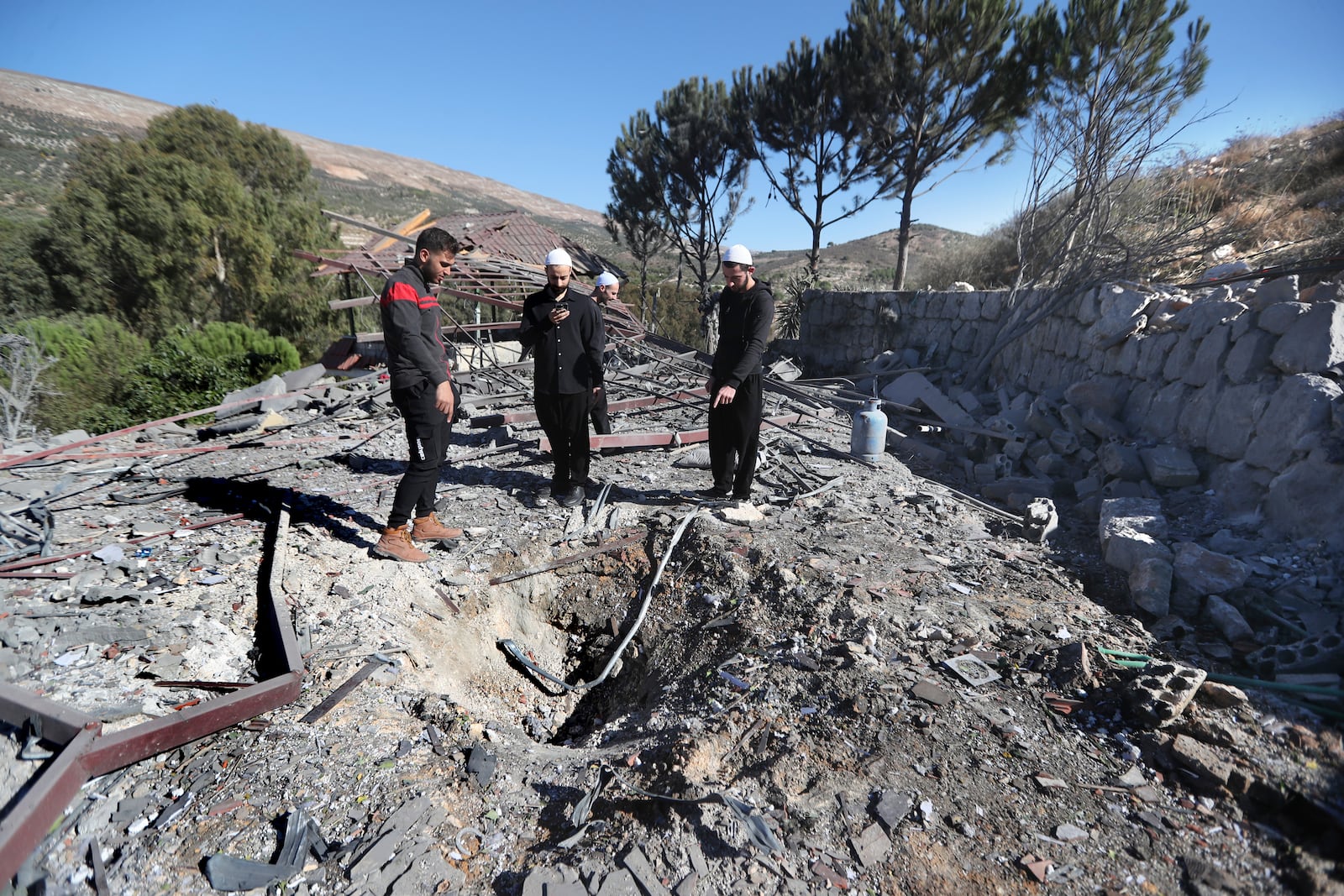 People observe the site where an Israeli airstrike hit a compound housing journalists, killing three media staffers from two different news agencies according to Lebanon's state-run National News Agency, in Hasbaya village, southeast Lebanon, Friday, Oct. 25, 2024. (AP Photo/Mohammed Zaatari)