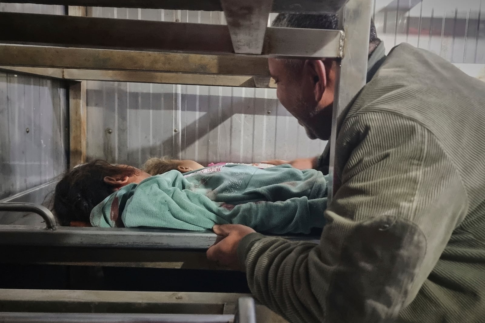 A man mourns as he places the body of a child in the hospital morgue following Israeli army airstrikes in Khan Younis, southern Gaza Strip, on Tuesday, March 18, 2025. (AP Photo/Mohammad Jahjouh)