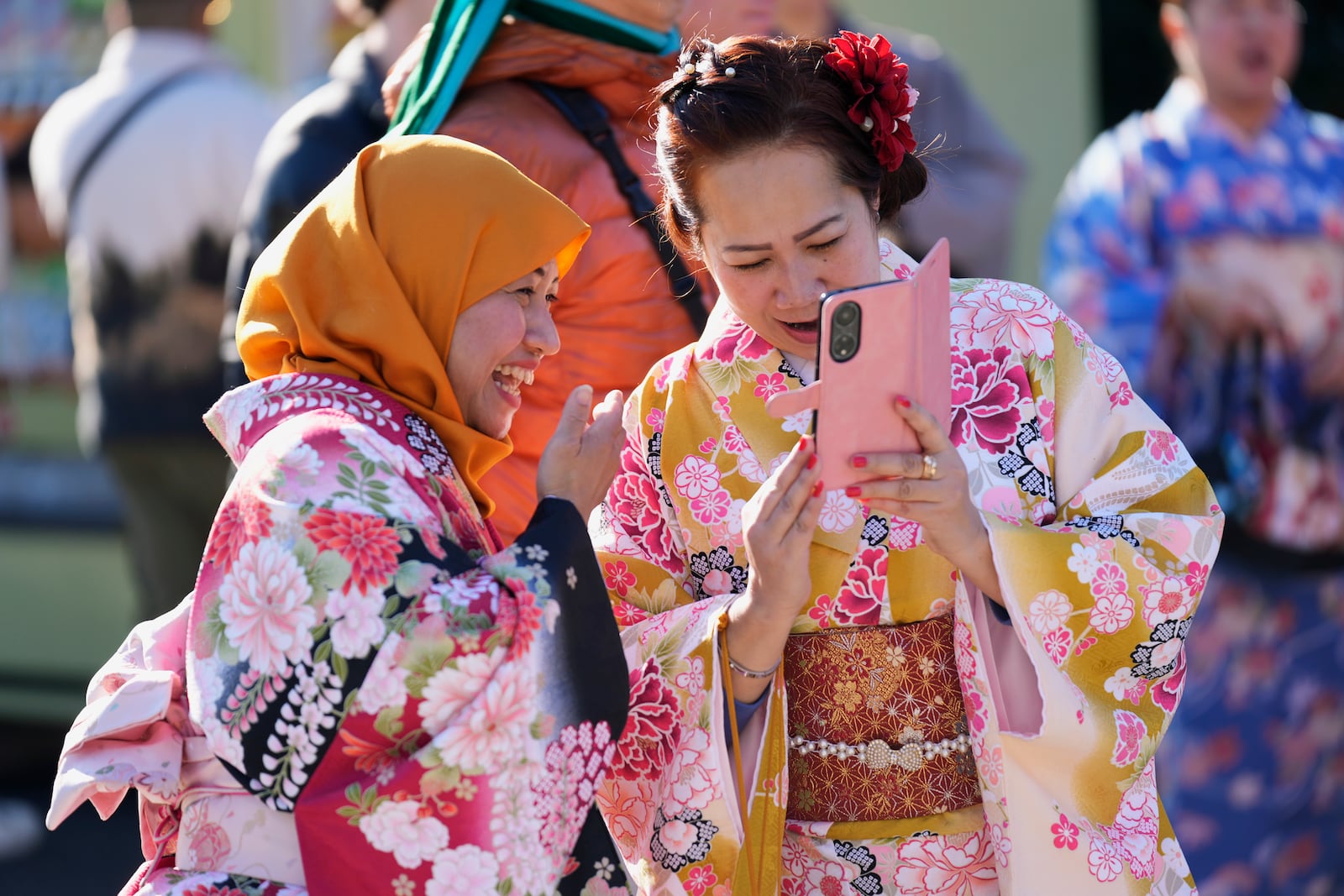 A woman from Nagoya, left, and her friend from Tokyo, both originally from Indonesia, react to their photos they just took as they visit Sensoji Buddhist temple on New Year's Eve in Tokyo, Tuesday, Dec. 31, 2024. (AP Photo/Hiro Komae)