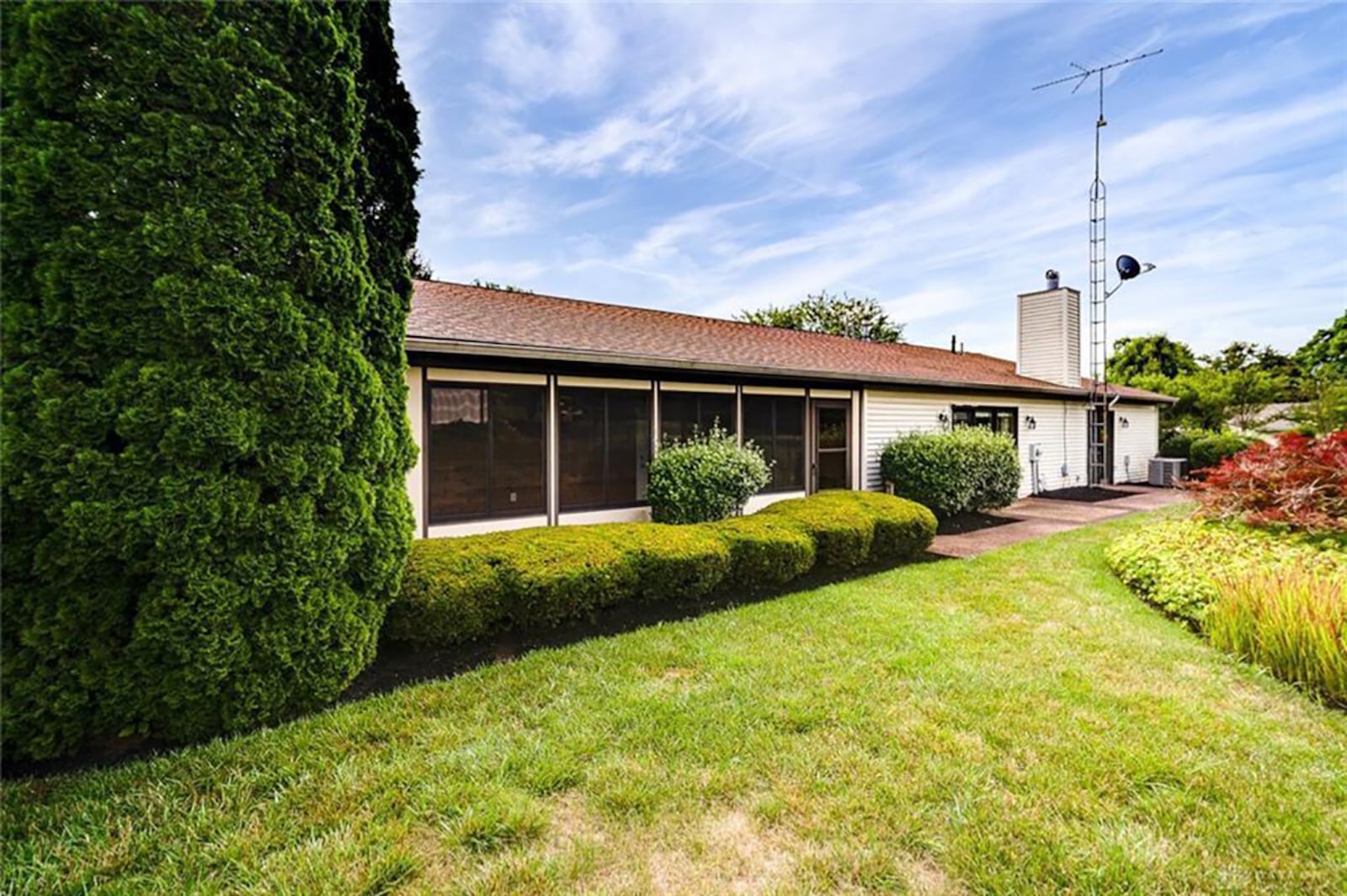 The rear of the home has a double wide concrete patio with two doors. There is also a 3-season room and satellite dish mounted to a tower. CONTRIBUTED PHOTO