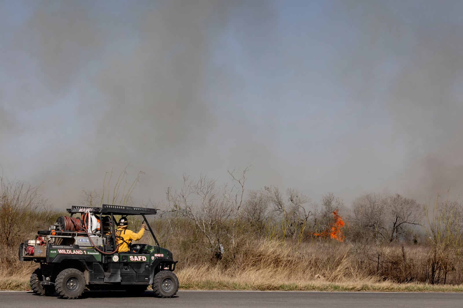 San Antonio Fire Department firefighters head towards a flame at the scene of a large brushfire on Tuesday, March 4, 2025, in Elmendorf, Texas. (Josie Norris/The San Antonio Express-News via AP)