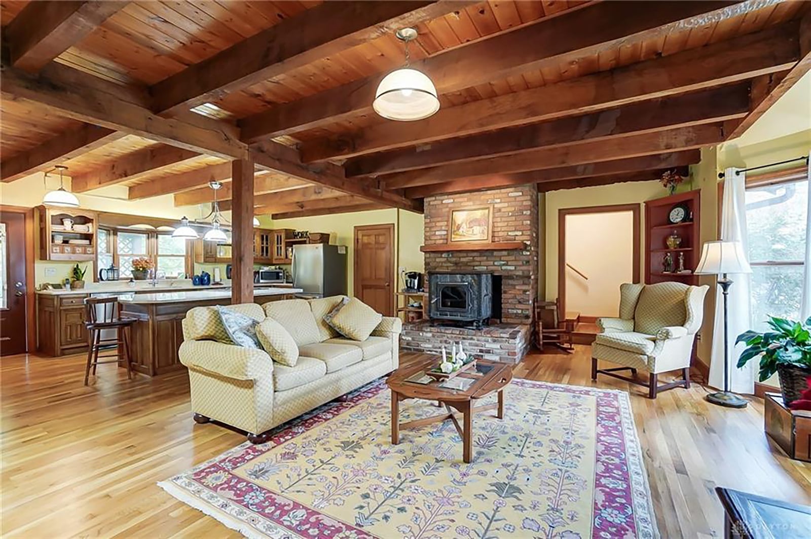 The open concept kitchen and family/dining room has wood flooring, beamed ceiling and a woodburning fireplace with stove insert.