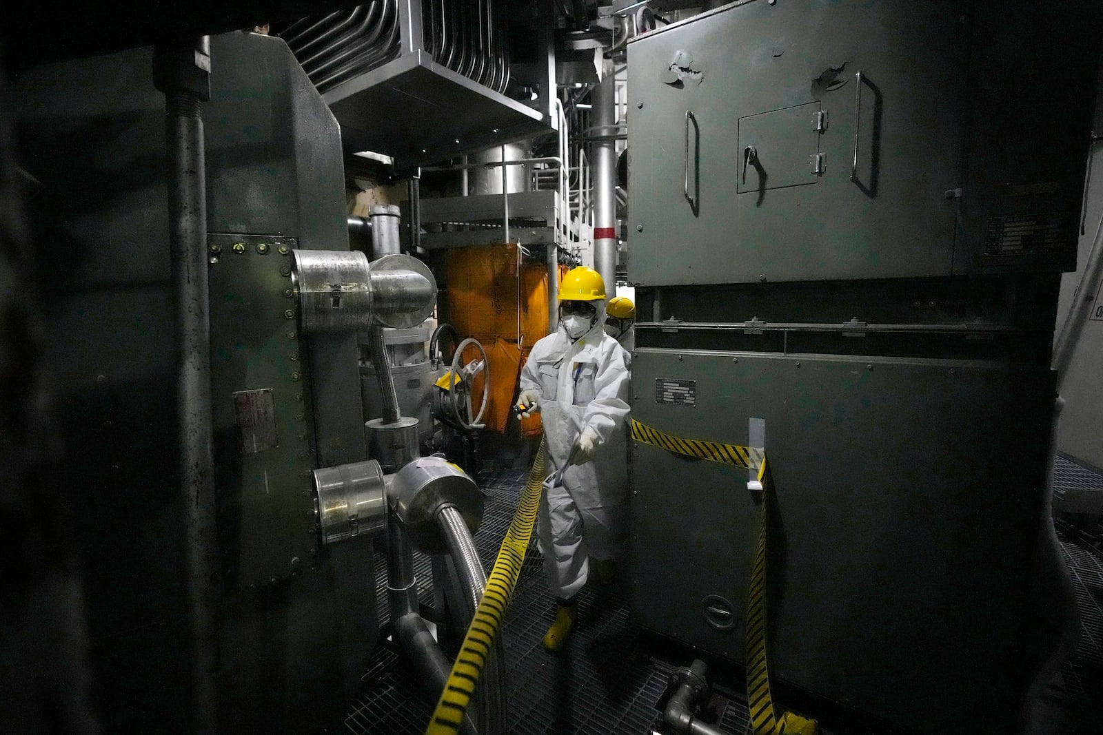 A worker in hazmat suit walks at the area under the Unit 5 reactor pressure vessel, which survived the earthquake-triggered tsunami in 2011, at the Fukushima Daiichi nuclear power plant, run by Tokyo Electric Power Company Holdings (TEPCO), in Futaba town, northeastern Japan, on Monday Feb. 20, 2025. (AP Photo/Eugene Hoshiko)