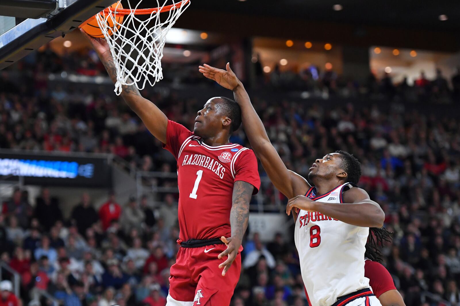 Arkansas guard Johnell Davis (1) drives to the basket past St. John's center Vince Iwuchukwu (8) during the first half in the second round of the NCAA college basketball tournament, Saturday, March 22, 2025, in Providence, R.I. (AP Photo/Steven Senne)