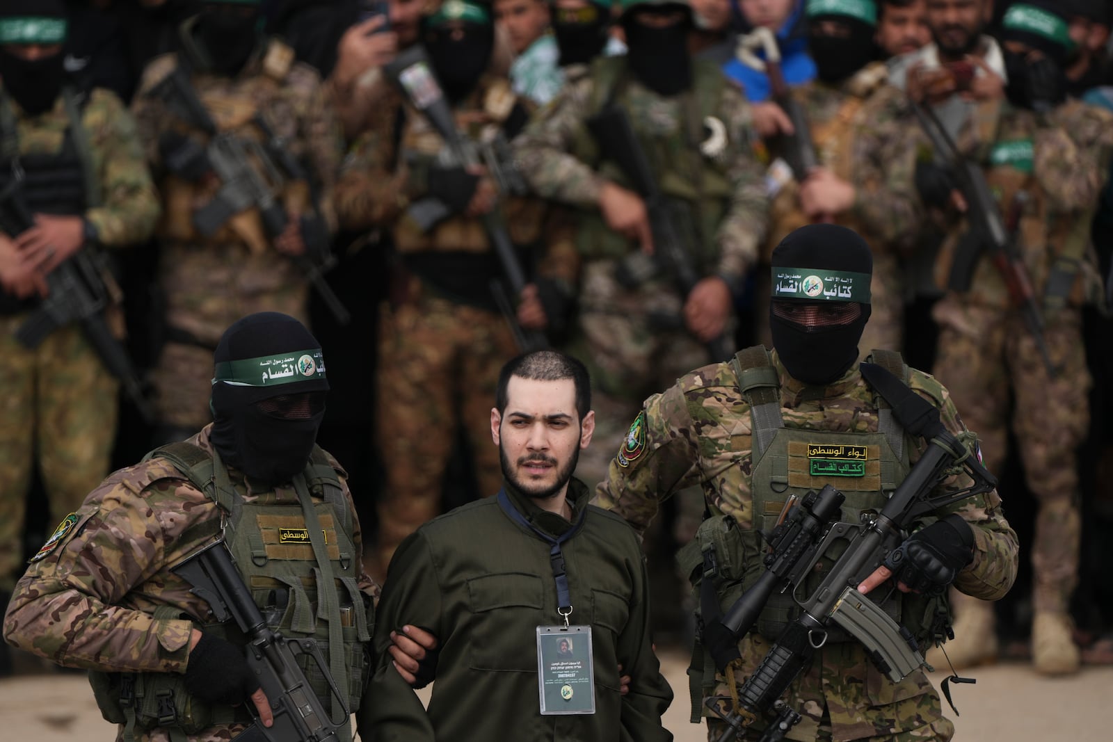 Israeli hostage Eliya Cohen, centre, is escorted by Hamas fighters before being handed over to the Red Cross in Nuseirat, central Gaza Strip, Saturday, Feb. 22, 2025. (AP Photo/Abdel Kareem Hana)