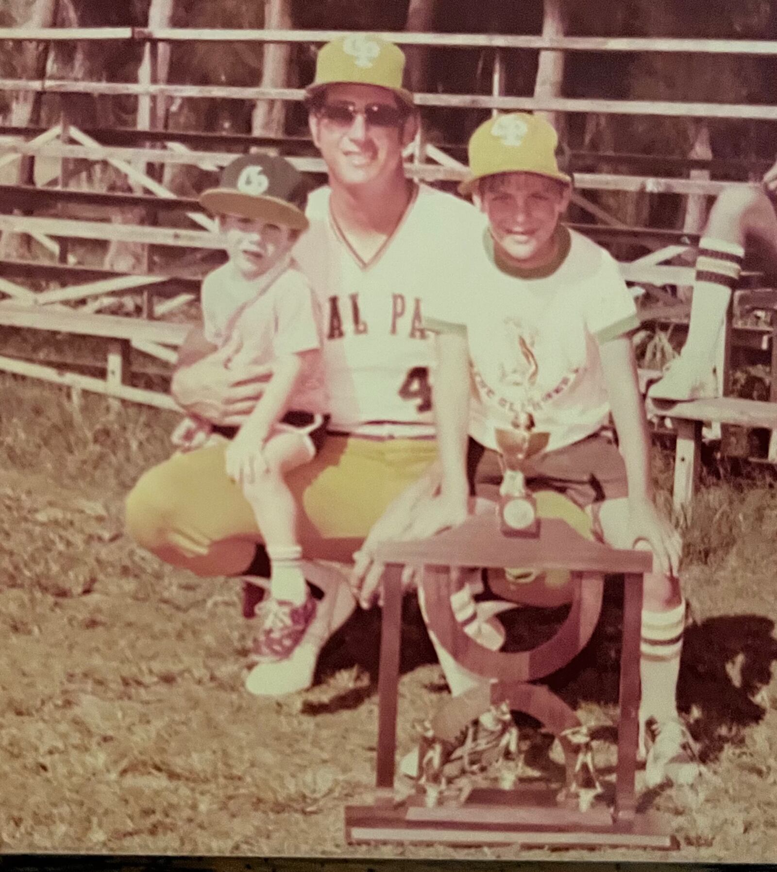 Three year old Darren Hertz (left) and his brother Jeff  with their dad, Steve Hertz, the former Major League baseball player, who coached the Coral Park High Rams back in Miami, Florisa to the Florida Division 4-A state baseball title in 1978. That’s the  state championship trophy in front of them. CONTRIBUTED