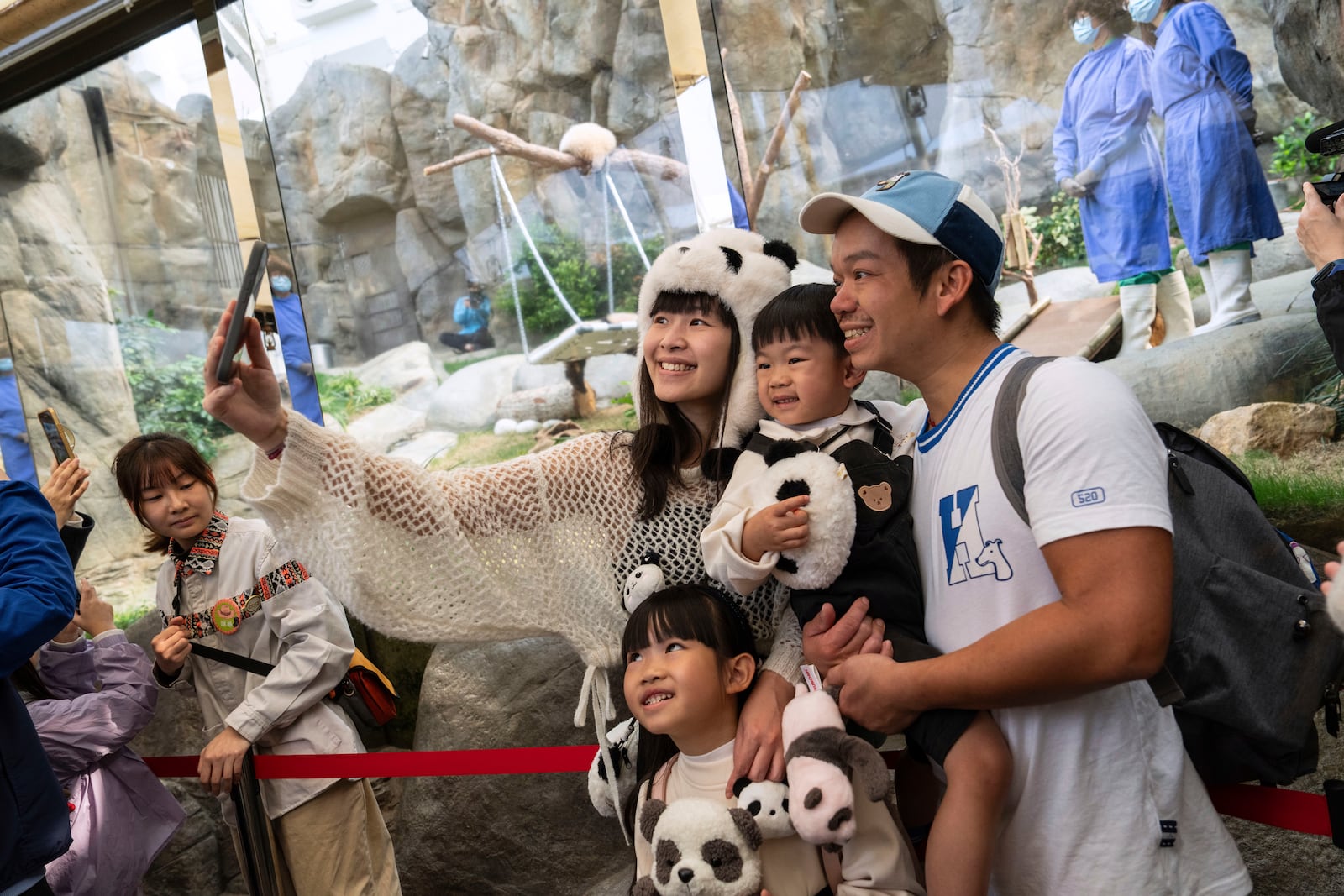 Visitors take selfie at the panda enclosure as the Hong Kong-born giant panda twin cubs make their debut appearance to public in Ocean Park in Hong Kong, Sunday, Feb. 16, 2025. (AP Photo/Chan Long Hei)