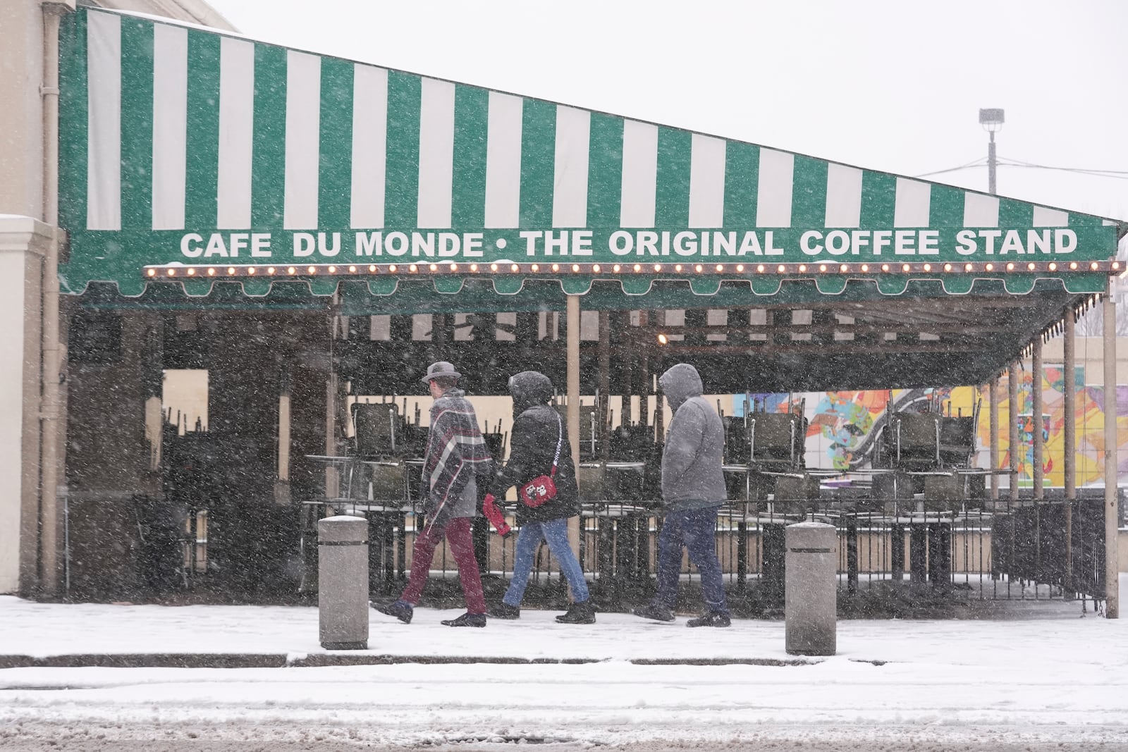 People walk by the empty Cafe Du Monde restaurant in the French Quarter in New Orleans, Tuesday, Jan. 21, 2025. (AP Photo/Gerald Herbert)