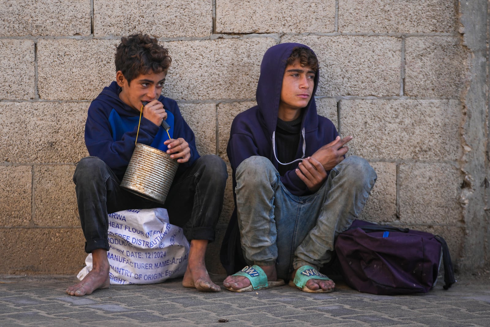 Two Palestinian boys wait to collect donated food at a food distribution center in Deir al-Balah, central Gaza Strip, Thursday Jan. 2, 2025. (AP Photo/Abdel Kareem Hana)