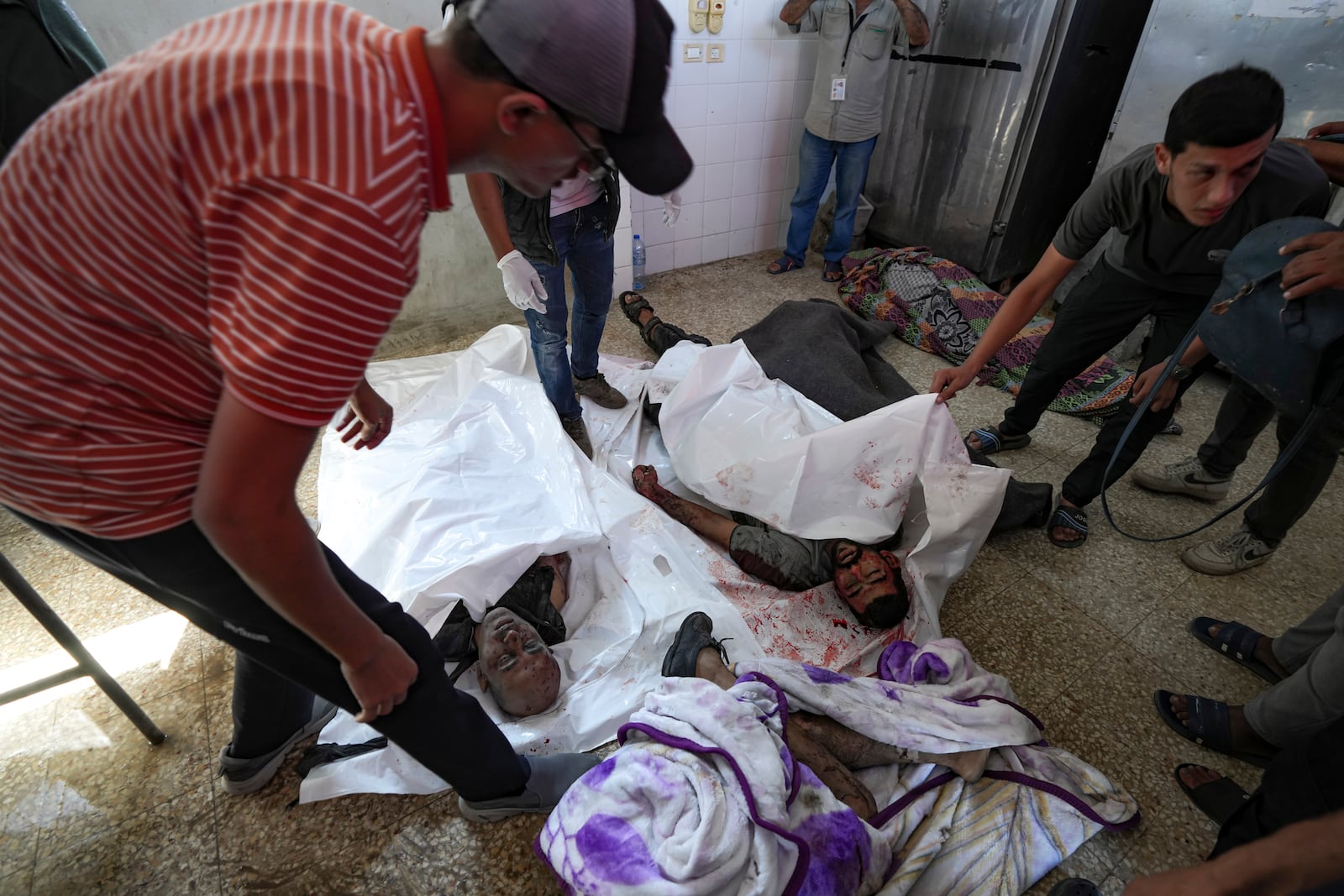 EDS NOTE: GRAPHIC CONTENT - Bodies of Palestinians killed in the Israeli bombardment of the Gaza Strip are brought to the hospital morgue in Deir al-Balah on Thursday, Oct. 10, 2024. (AP Photo/Abdel Kareem Hana)