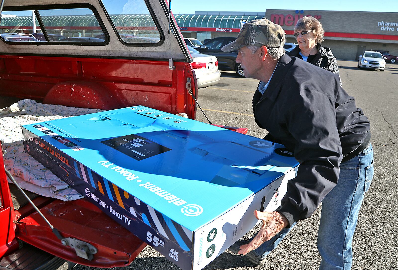 Lee and Carolyn Cremeans put their new television in the back of their truck after purchasing it at Meijer in Springfield Tuesday. BILL LACKEY/STAFF