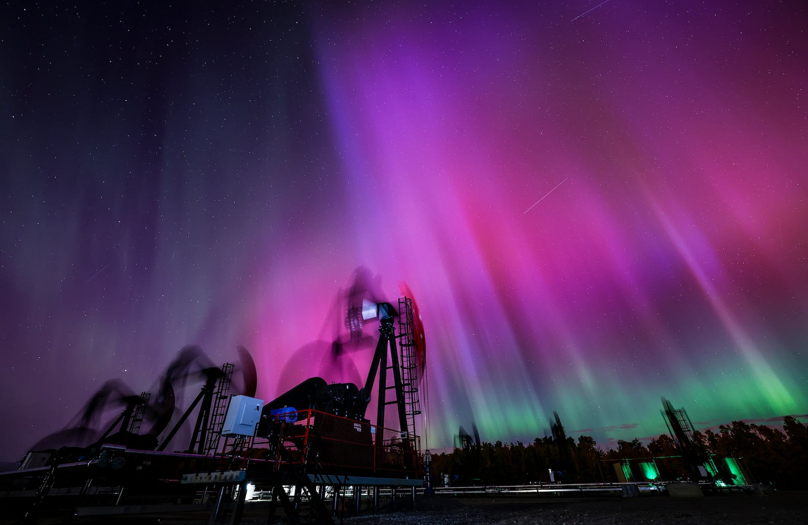 An aurora borealis, also known as the northern lights, makes an appearance over pumpjacks as they draw out oil and gas from well heads near Cremona, Alberta, Thursday, Oct. 10, 2024. (Jeff McIntosh/The Canadian Press via AP)