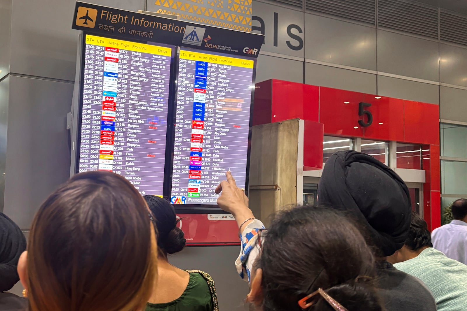 People read an electronic display at the New Delhi international airport showing that an American Airlines flight AA292 from New York was diverted to Rome, instead of its scheduled arrival at New Delhi, India, Sunday, Feb. 23, 2025. (AP Photo/Manish Swarup)