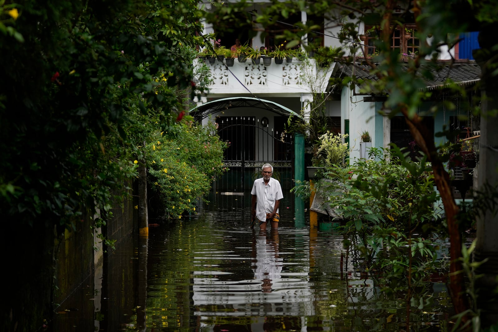 A man wades through water outside his flooded house in Colombo, Sri Lanka, Sunday, Oct. 13, 2024. (AP Photo/Eranga Jayawardena)