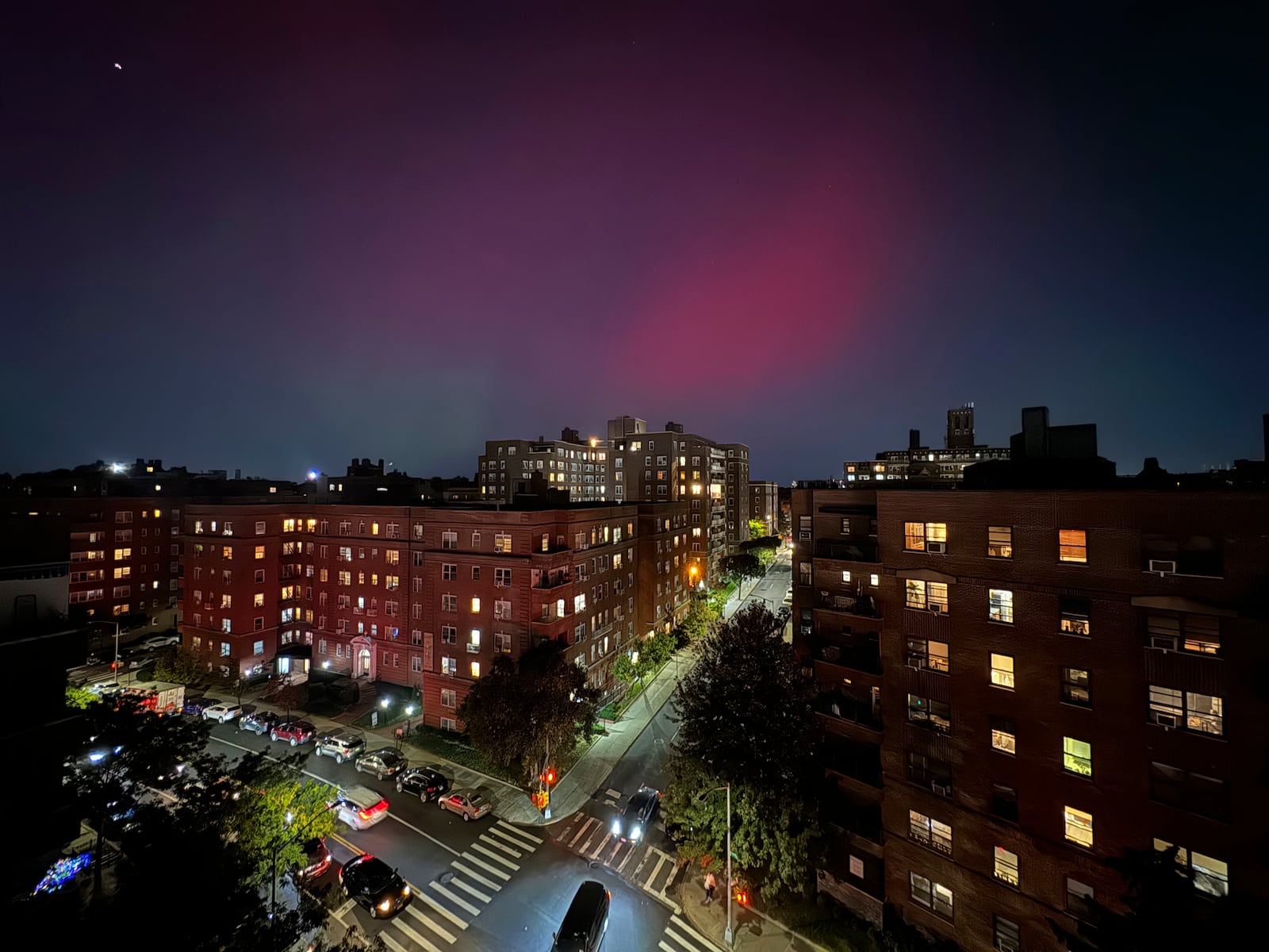 The Northern lights glow in the night sky above apartment buildings in the Queens borough of New York, Thursday, Oct. 10, 2024. (AP Photo/Daniel P. Derella)