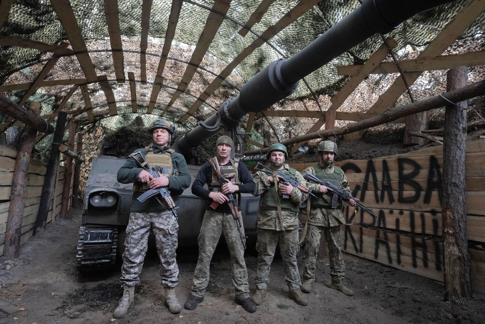 Ukrainian servicemen of the 92nd separate assault brigade pose for photo at their 155mm M-109 "Paladin" howitzer on the frontline near Vovchansk, Kharkiv region, Ukraine, Monday, Oct. 28, 2024, with sign in the background reads "Glory to Ukraine". (AP Photo/Efrem Lukatsky)