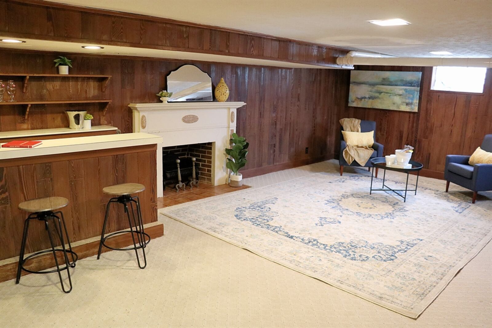 The home features a large family room with a decorative fireplace and a peninsula dry bar. Wood paneling covers the walls.