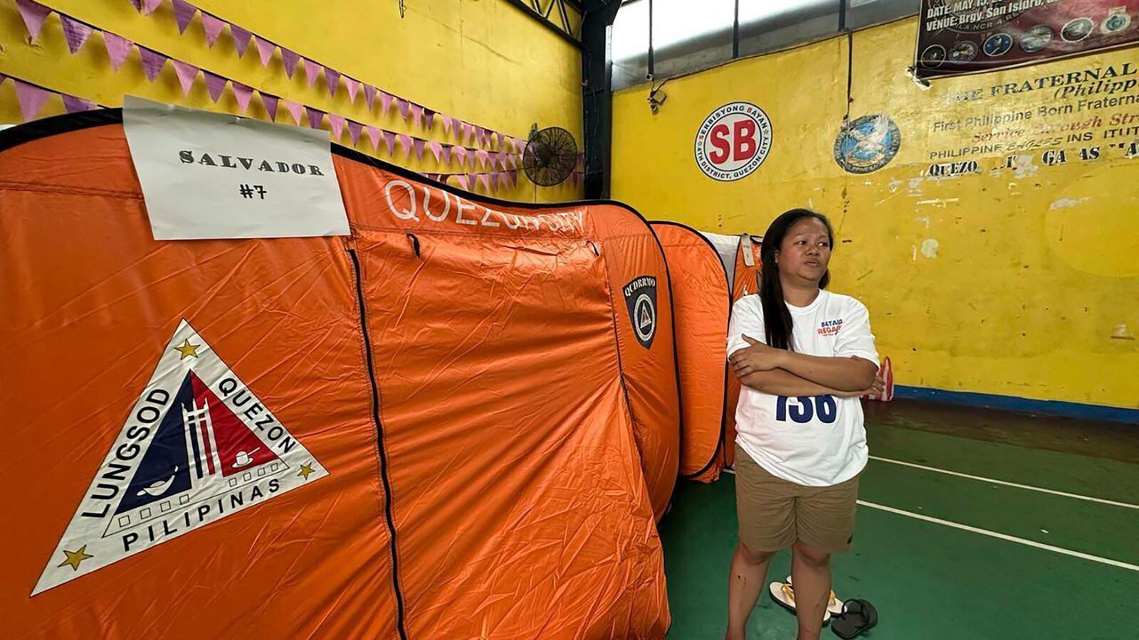 Fire survivor, Beverly Salvador, a 33-year old online seller who lost all their belongings, stands beside a tent inside a gymnasium set as an evacuation center in suburban Quezon city, Philippines Thursday, Feb. 27, 2025. (AP Photo/Joeal Calupitan)