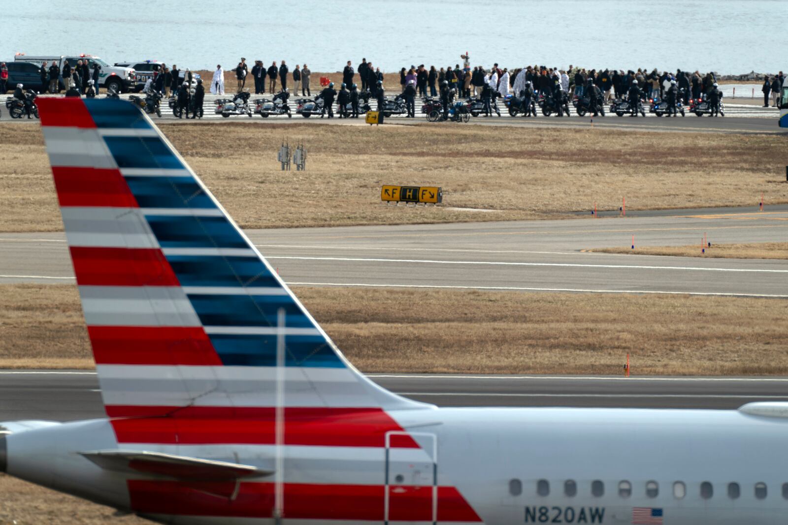 Family members of the victims of a mid-air collision between an American Airlines jet and an Army helicopter gather at the end of runway 33 near the wreckage site in the Potomac River at Ronald Reagan Washington National Airport, Sunday, Feb. 2, 2025, in Arlington, Va. (AP Photo/Jose Luis Magana)