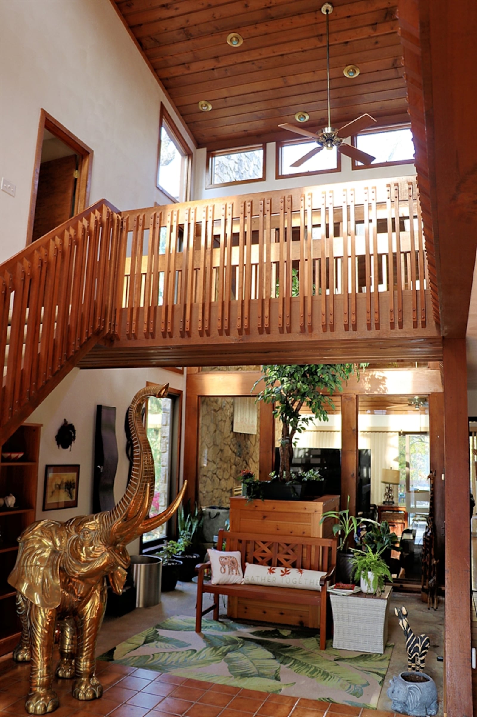 Vaulted ceilings are accented by wood planks and the foyer has six skylights above the atrium. Formal areas encircle the atrium filling the space with natural light. A step-down from the foyer is the formal living room with a triangular sitting area with floor-to-ceiling windows.