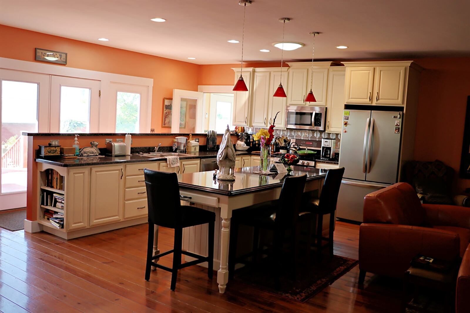 Both the dining room and the family room open into the great room addition. The open space has polished hardwood flooring and sitting area, bar area, large island with table setting and a peninsula counter that provides plenty of work space for the kitchen. Quartz countertops complement the white cabinetry. CONTRIBUTED PHOTO BY KATHY TYLER