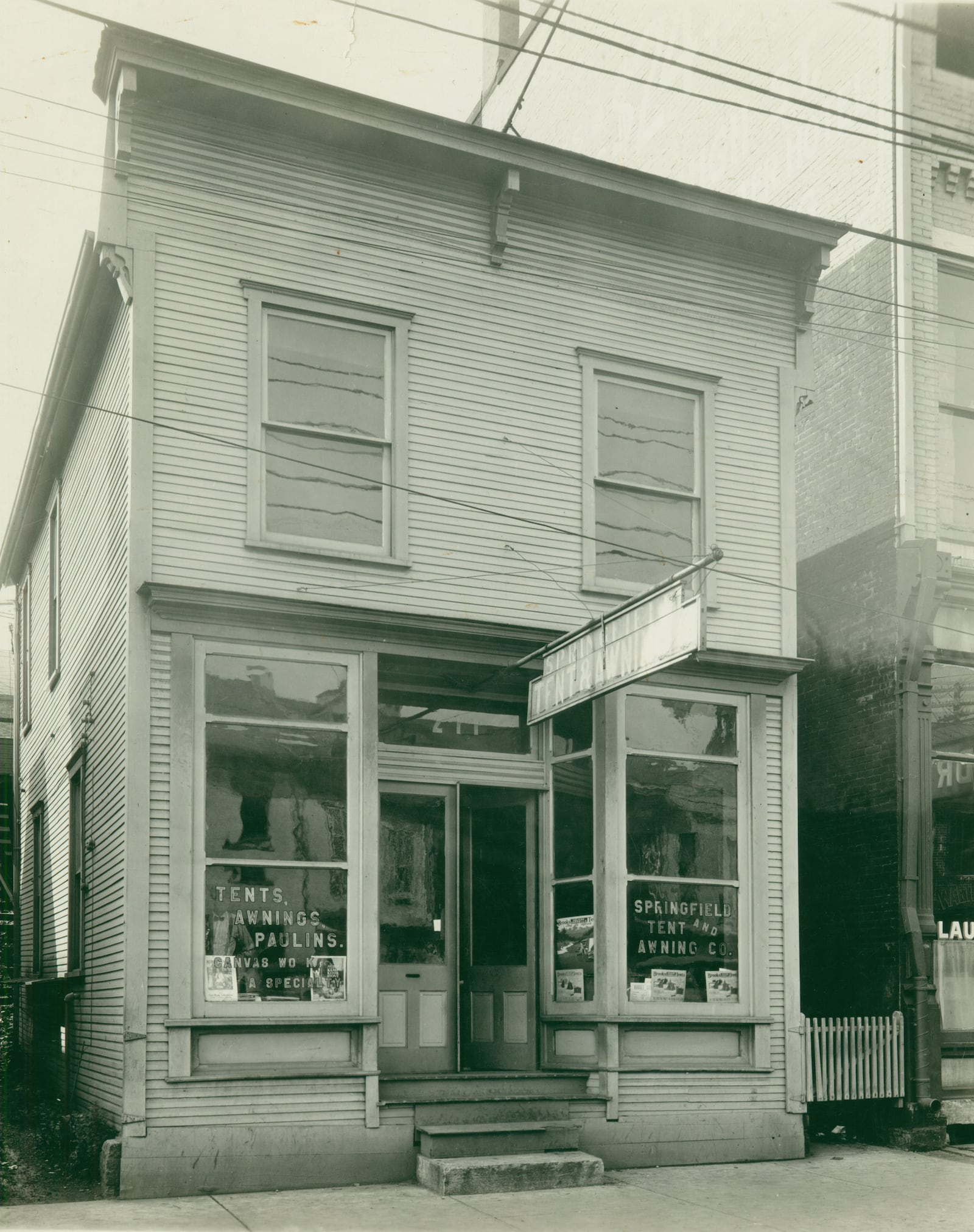 Around 1880, the Dial family came to Ohio from Illinois and settled in Dayton. The elder Dial, Absalom, worked as a salesman, and following is death in 1886, his young son, George Hooker Dial began work as an awning maker. By 1898, George struck out on his own, briefly working in Columbus before moving to Springfield to start the Springfield Tent and Awning Company, which was originally located on W. Main Street. George moved to Columbus in 1910 and continued in the tent and awning business, but the business he had started remained in Springfield. They made awnings, tents, flags, and camp furniture, often showcasing the awning work they did for many residences around town. They are shown here in September 1929 at 211 E. Main Street. PHOTO COURTESY OF THE CLARK COUNTY HISTORICAL SOCIETY