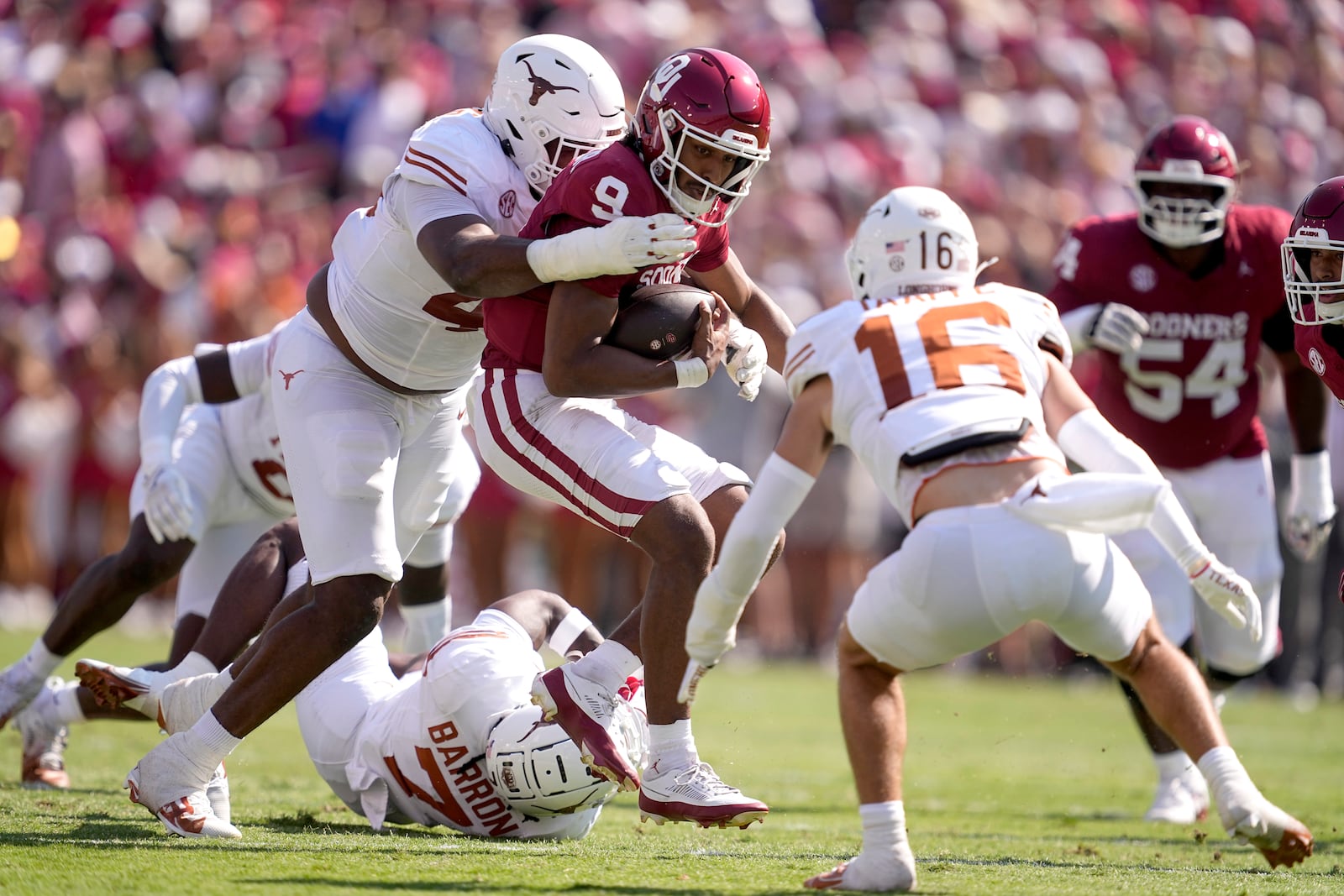 Oklahoma quarterback Michael Hawkins Jr. (9) gains short yards on a keeper as Texas defensive lineman Vernon Broughton, left, and Michael Taaffe (16) make the stop in the first half of an NCAA college football game in Dallas, Saturday, Oct. 12, 2024. (AP Photo/Tony Gutierrez)