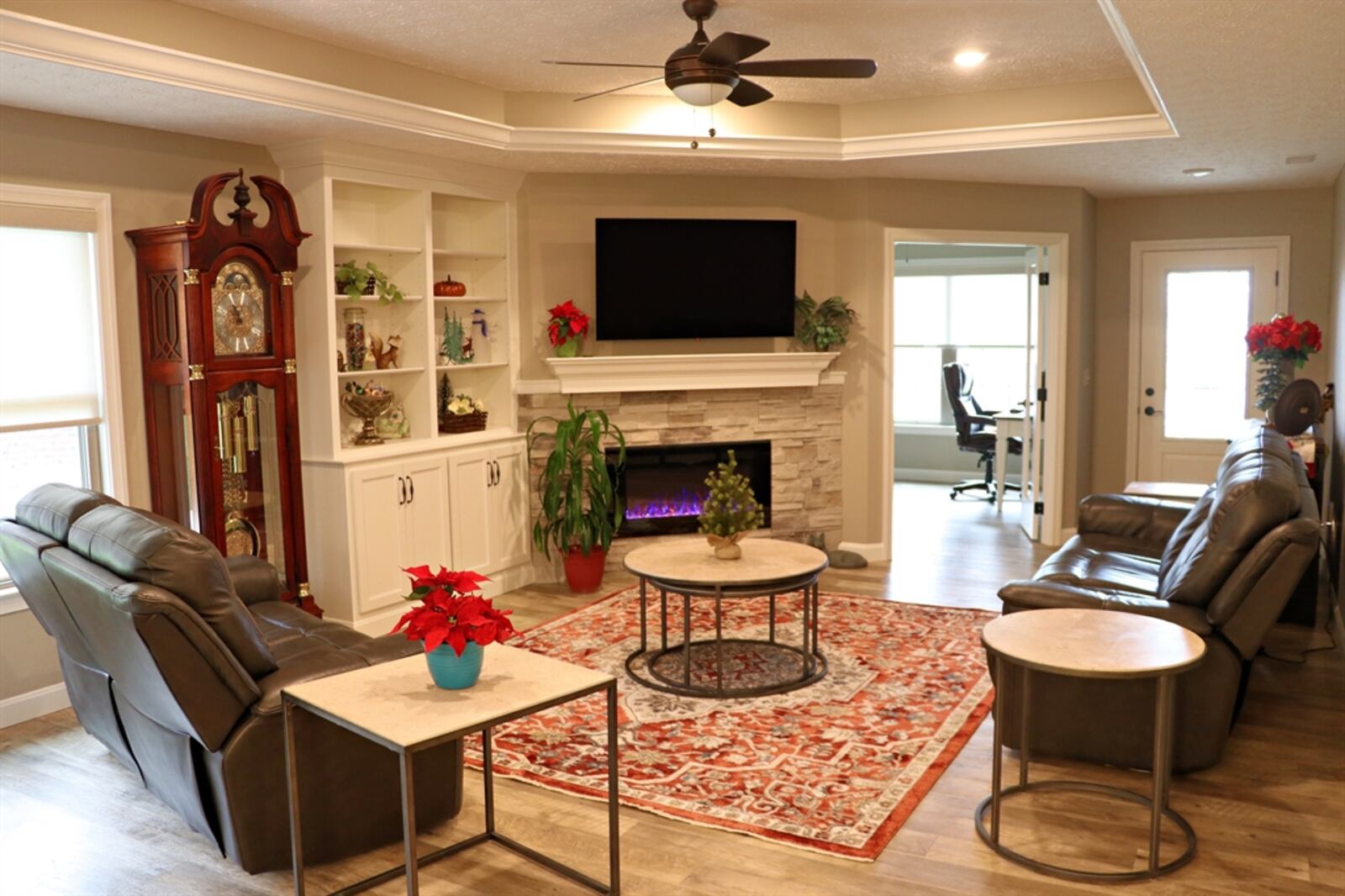 Stack-stone accents surround the electric fireplace, which has remote features. There is a dentil wooden mantel. 