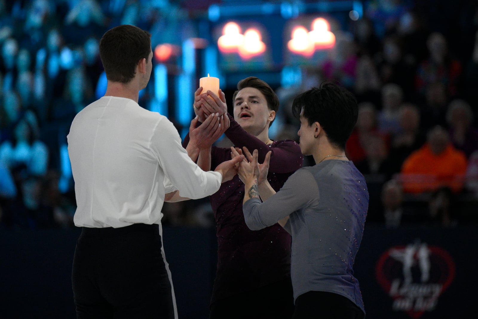 Cast members hold up a candle Sunday, March 2, 2025, in Washington at the Legacy on Ice event, a figure skating tribute to support the families and loved ones affected by the Jan. 29 aviation incident. (AP Photo/Nick Wass)