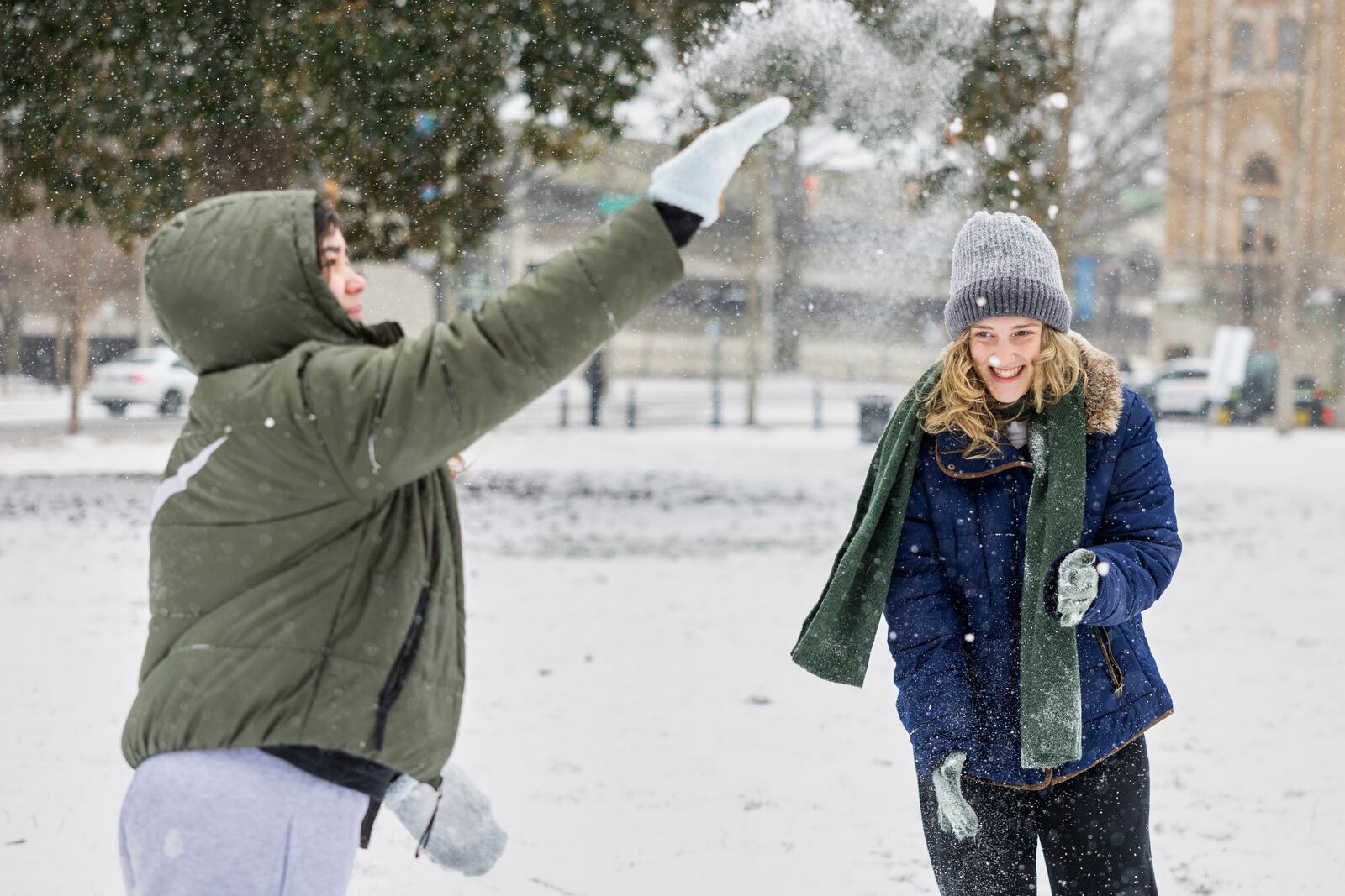 Ellie Sims, right, laughs as Amilia Muller's snowball disintegrates mid-air as they play in Monroe Park, Wednesday, Feb. 19, 2025, in Richmond, Va. (Margo Wagner/Richmond Times-Dispatch via AP)