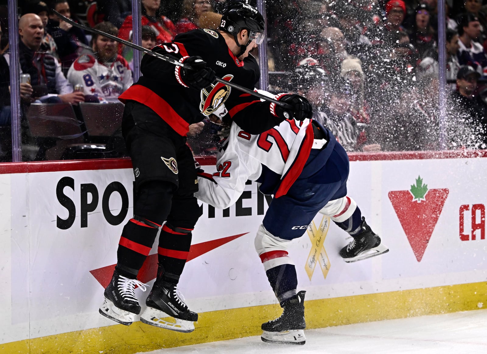 Ottawa Senators' Travis Hamonic (23) hits Washington Capitals' Brandon Duhaime (22) along the boards during first-period NHL hockey game action in Ottawa, Ontario, Thursday, Jan. 30, 2025. (Justin Tang/The Canadian Press via AP)