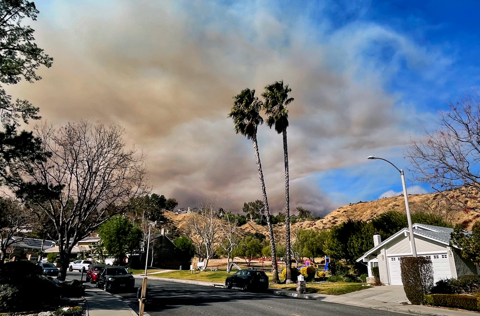 A large plume of smoke rises from Castaic Lake seen behind a neighborhood in Santa Clarita, Calif. on Wednesday, Jan. 22, 2025. (AP Photo/Marcio Jose Sanchez)