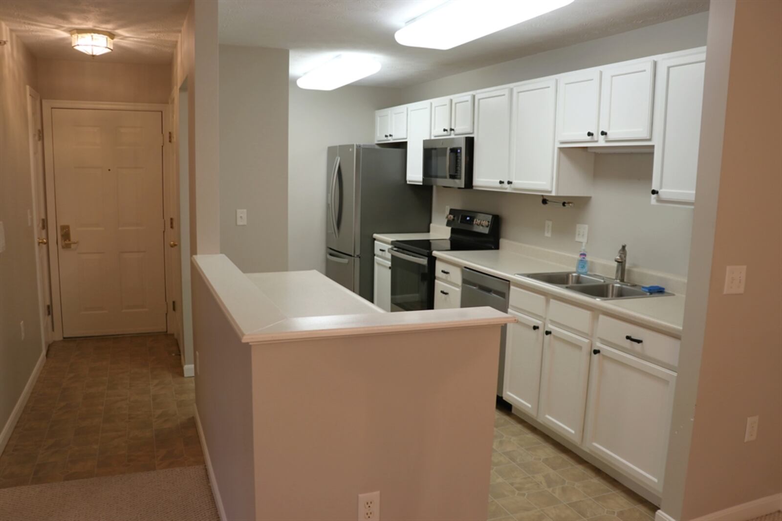 The kitchen has a wall of cabinetry with matching counters that surround appliances, which include a range, microwave, dishwasher and refrigerator. 