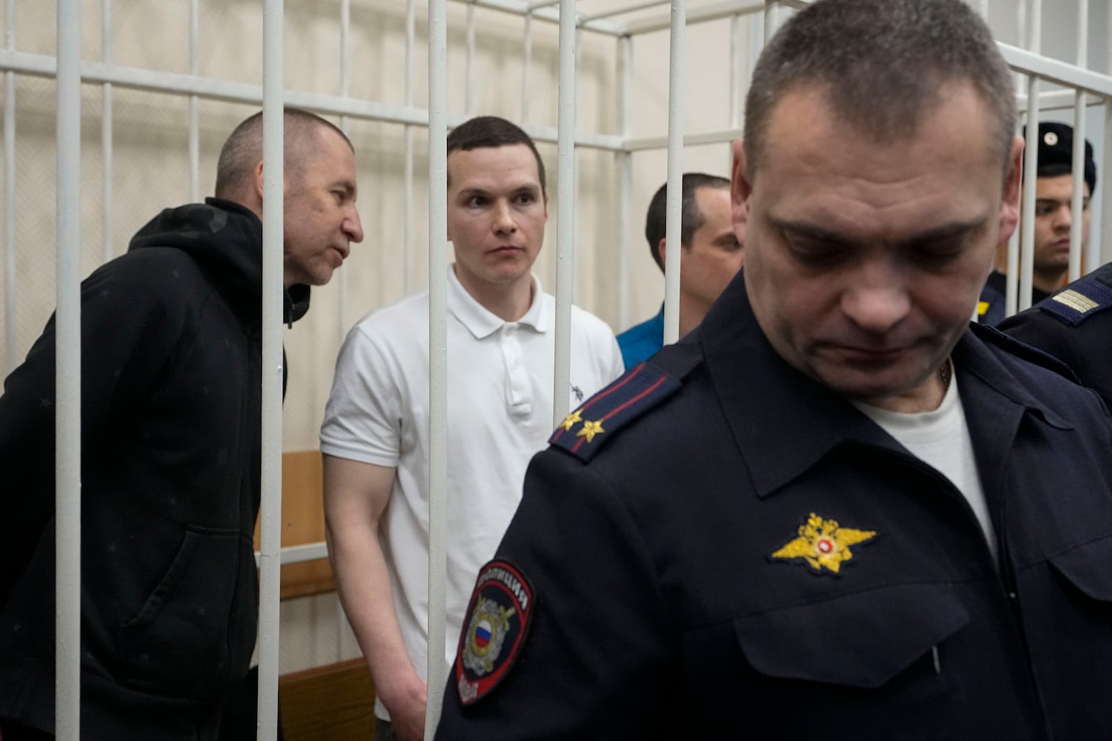 Lawyers from left, Igor Sergunin, Alexei Liptser and Vadim Kobzev, all who once represented late opposition leader Alexei Navalny, stand behind a police officer in a courtroom in Petushki, Vladimir region, about 120 kilometers (75 miles) east of Moscow, Russia, Friday, Jan. 17, 2025. (AP Photo/Pavel Bednyakov)