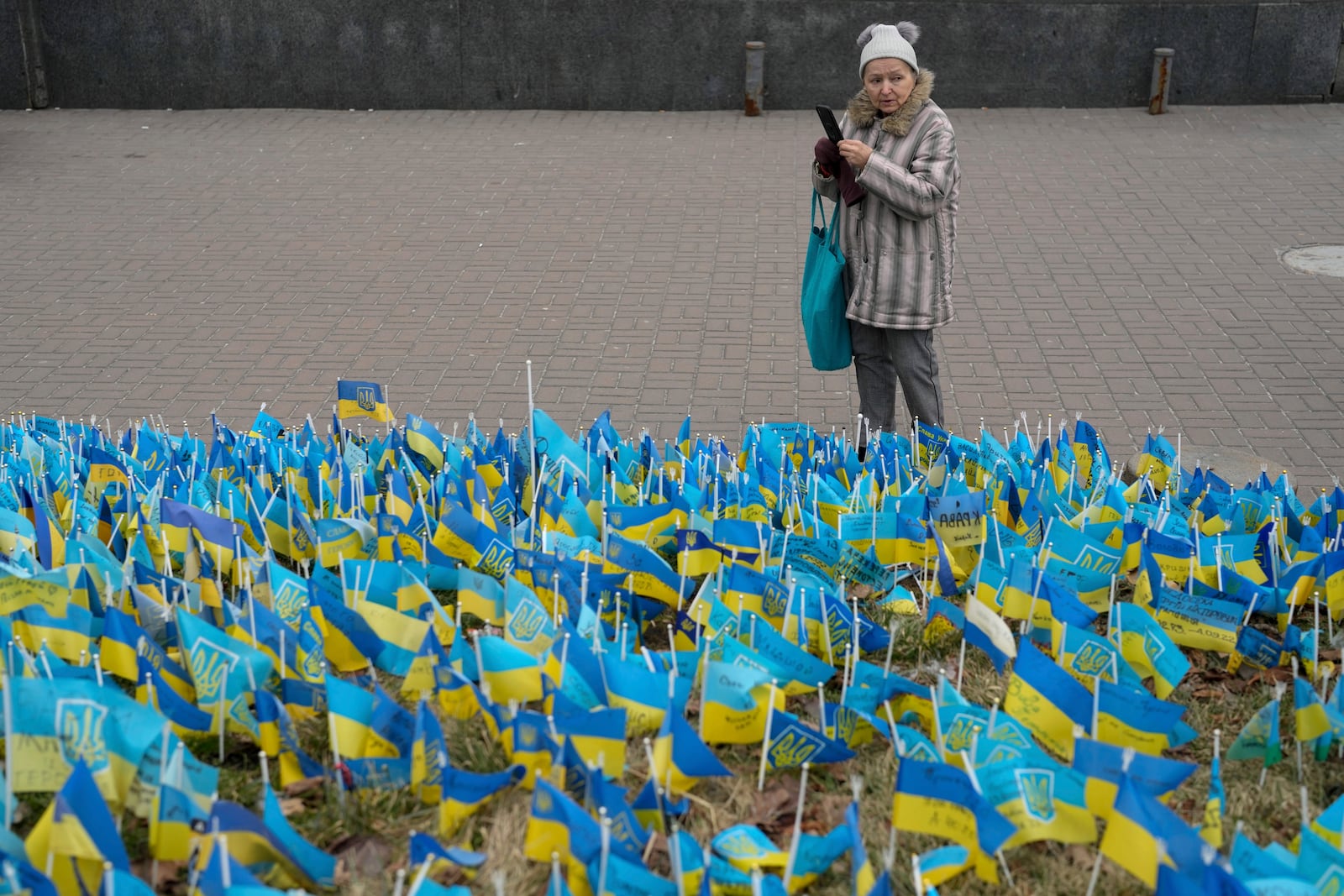 A woman takes a picture at the memorial for those killed during the war in Independence Square in Kyiv, Ukraine, Friday, Feb. 24, 2023. (AP Photo/Thibault Camus)