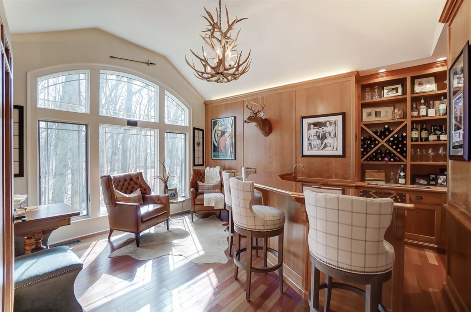 French doors open into the paneled pub with a vaulted ceiling. A peninsula bi-level counter wraps around the bottle nook. The copper counter has a hand-pounded, copper sink. 