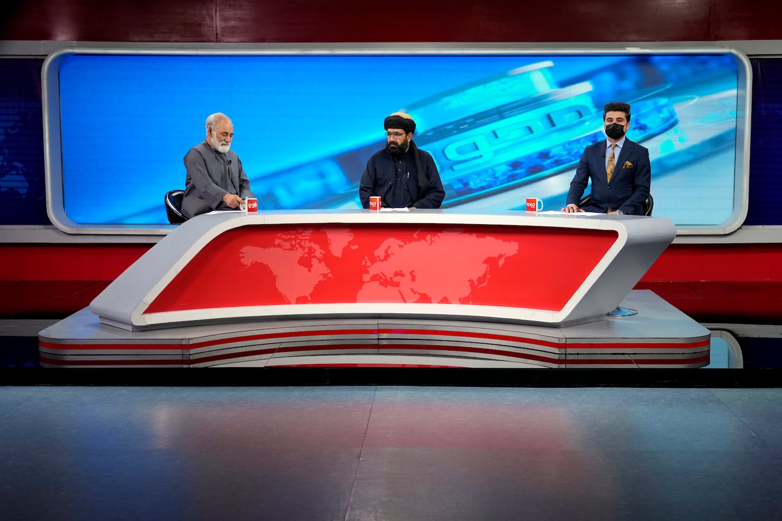 FILE - TV anchor Nesar Nabil wears a face mask to protest the Taliban's new order that female presenters cover their faces, as he reads the news on TOLOnews, in Kabul, Afghanistan, Sunday, May 22, 2022. (AP Photo/Ebrahim Noroozi, File)