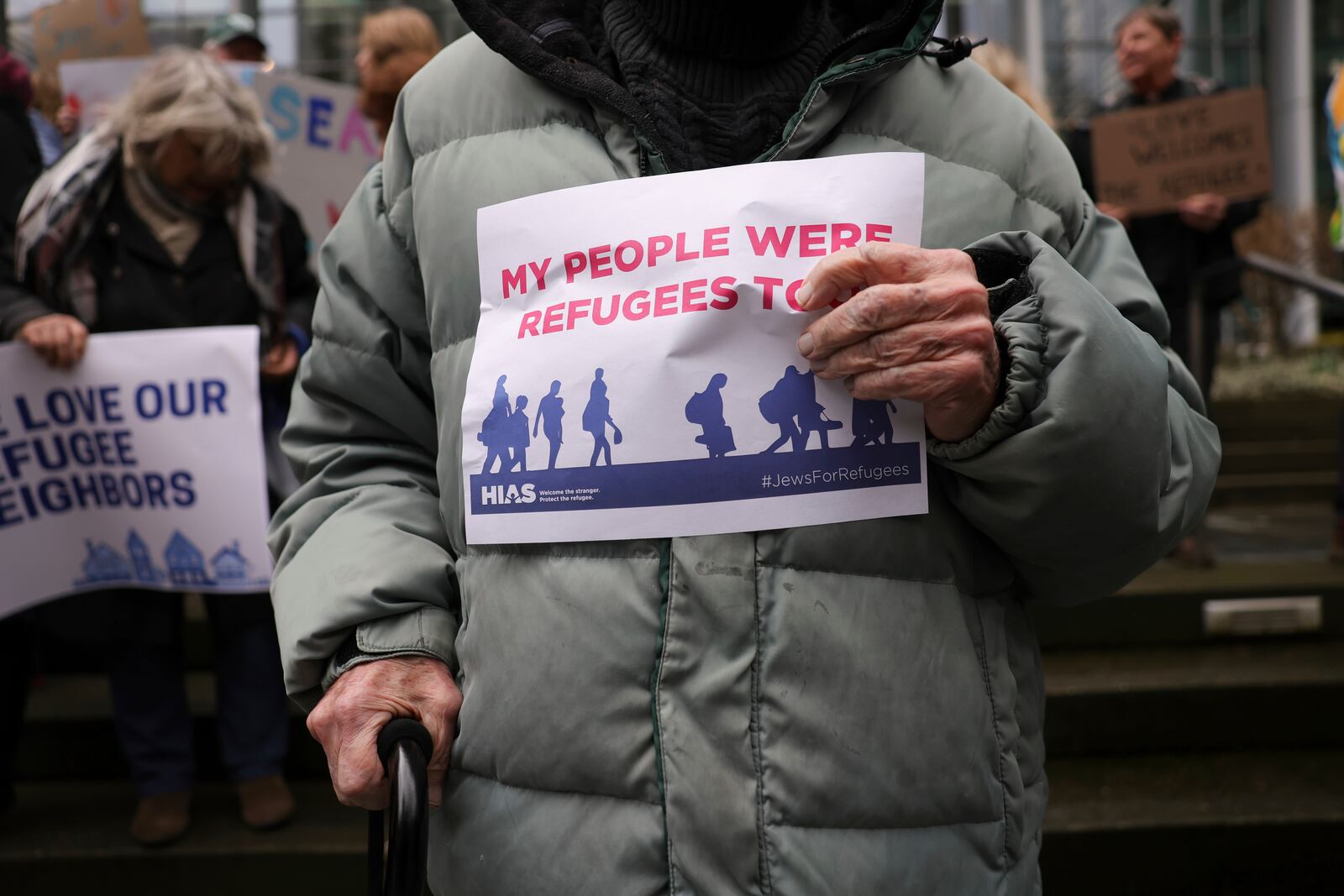 People hold signs as they gather outside the U.S. District Court after a federal judge blocked President Donald Trump's effort to halt the nation's refugee admissions system Tuesday, Feb. 25, 2025, in Seattle. (AP Photo/Ryan Sun)