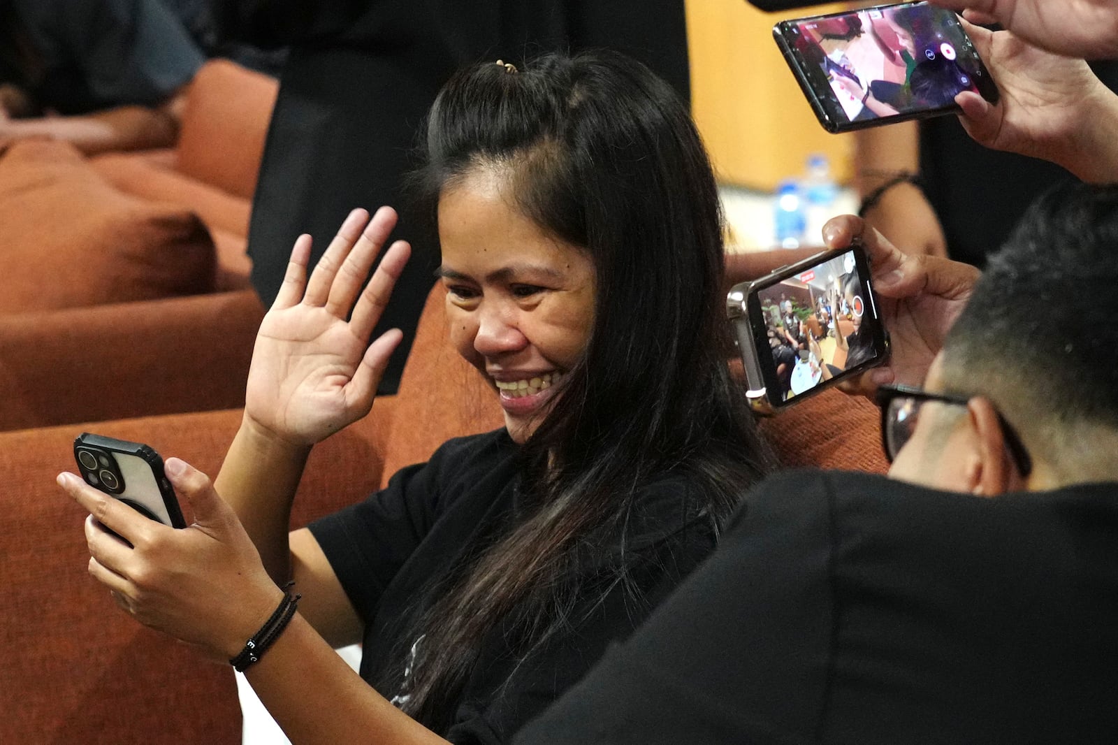 Mary Jane Veloso, center, a Filipina who was on death row in Indonesia and was nearly executed by firing squad in 2015, reacts as she uses a mobile phone for a video call after arrival at Soekarno-Hatta International Airport for her repatriation to the Philippines, in Tangerang, Indonesia, Tuesday, Dec. 17, 2024. (AP Photo/Tatan Syuflana)